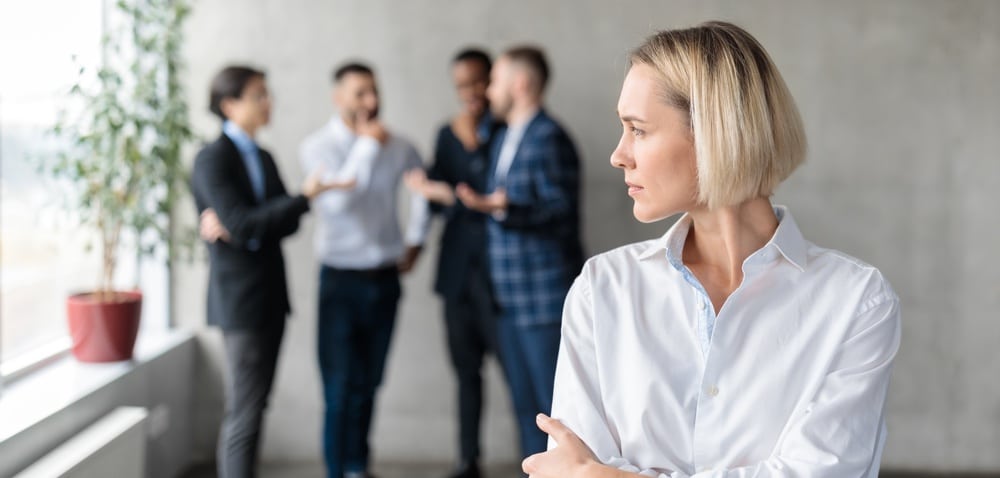 male coworkers whispering with a woman unhappy at forefront