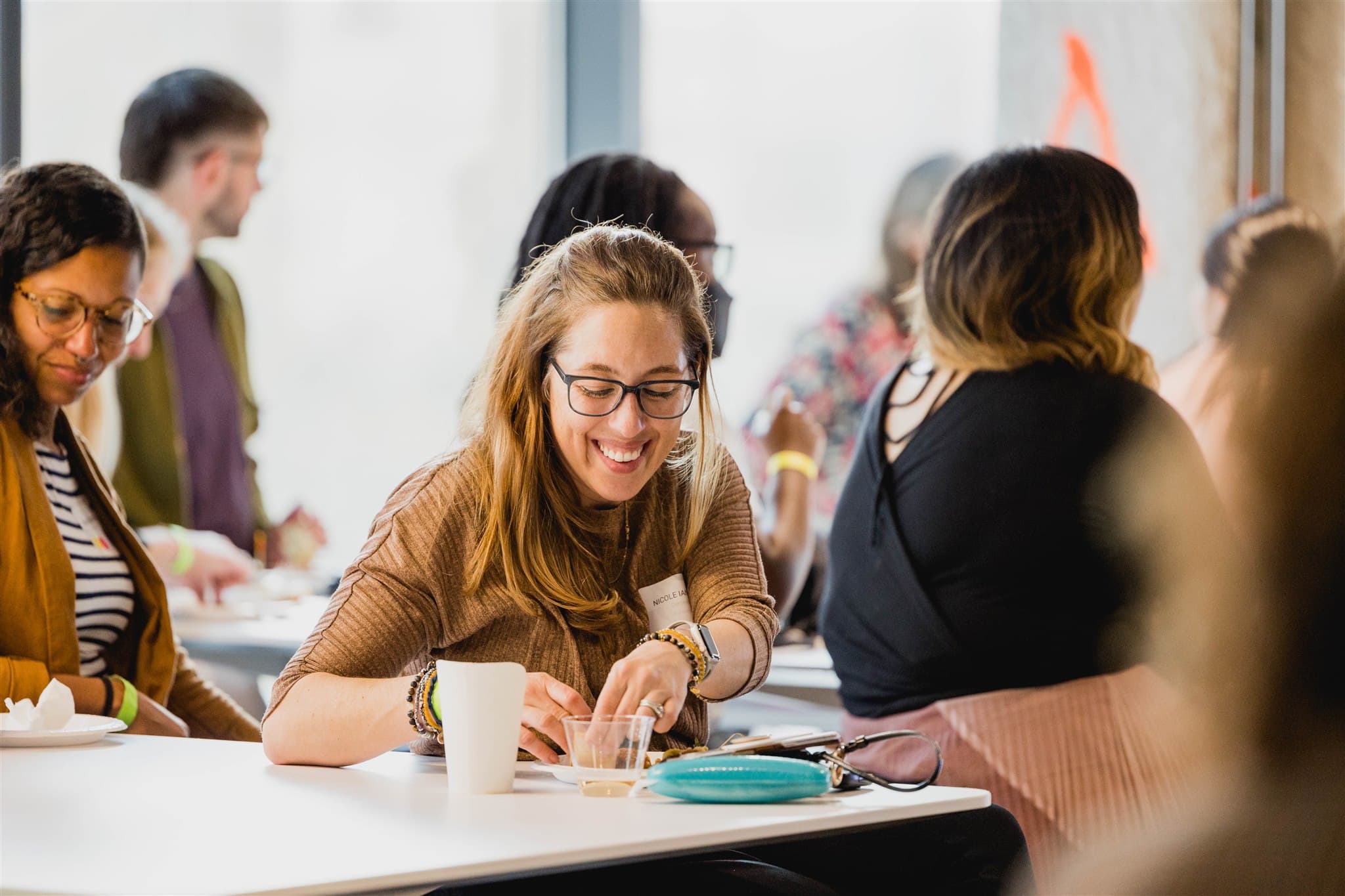 White woman smiling and eating at a table with other people at a Inclusion Geeks Geek Out