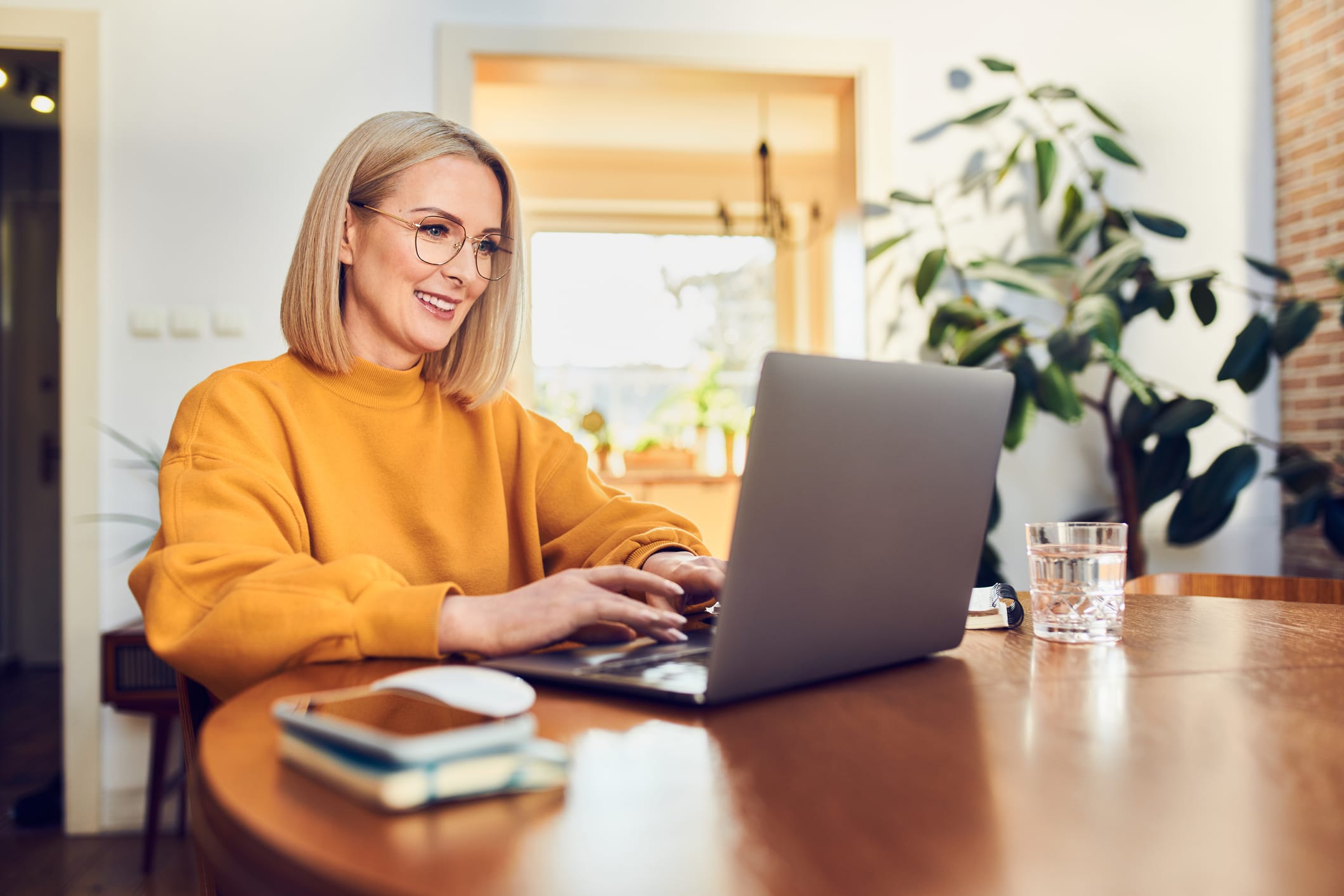 Woman sitting at a dinning table working at home on laptop.