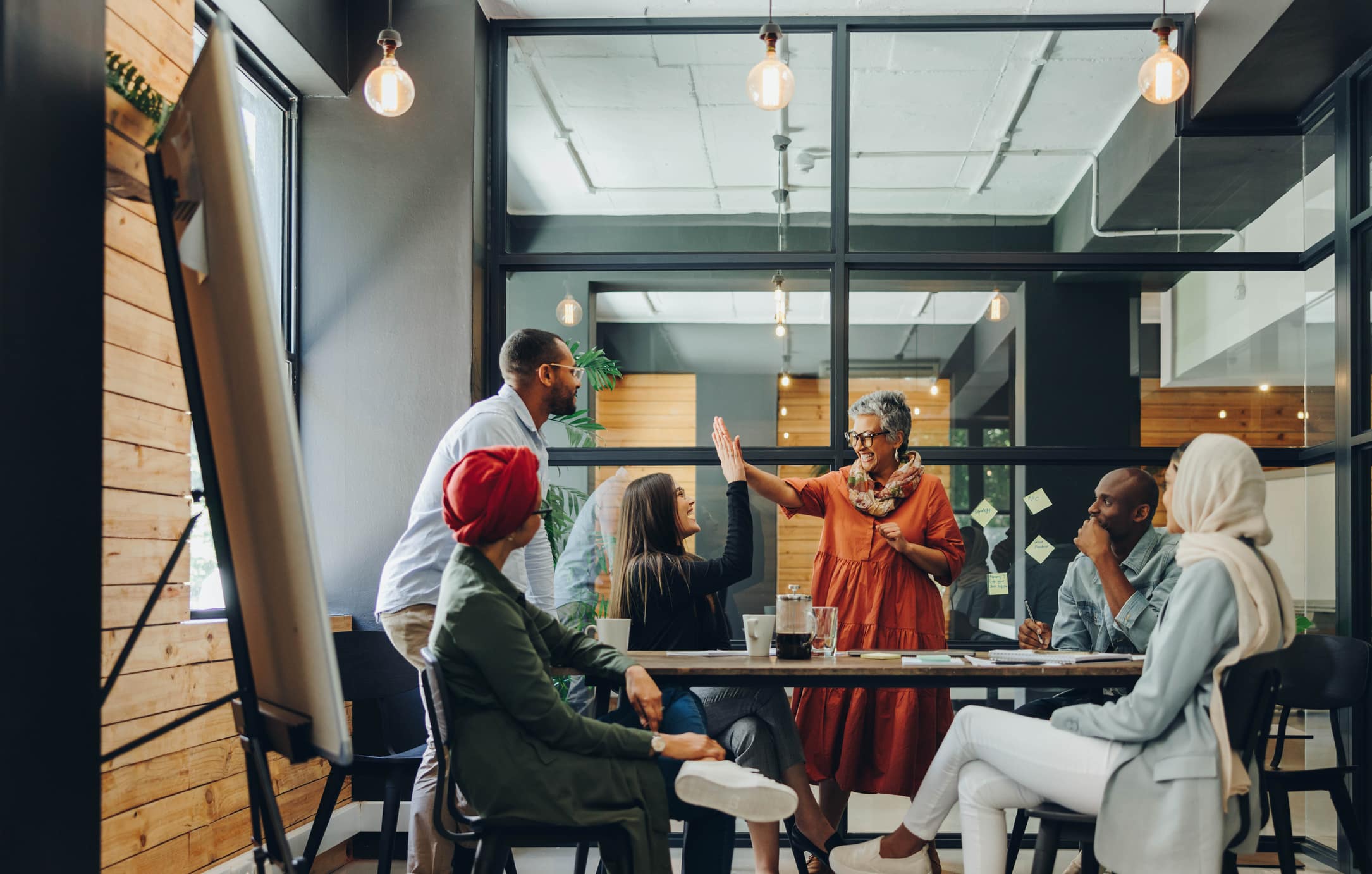 Successful businesswomen high-fiving each other during an office meeting.