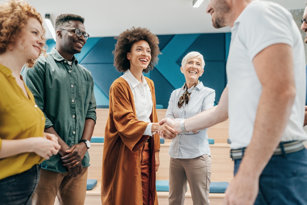 Businesswoman shaking hands with her colleague during a group meeting in the office.