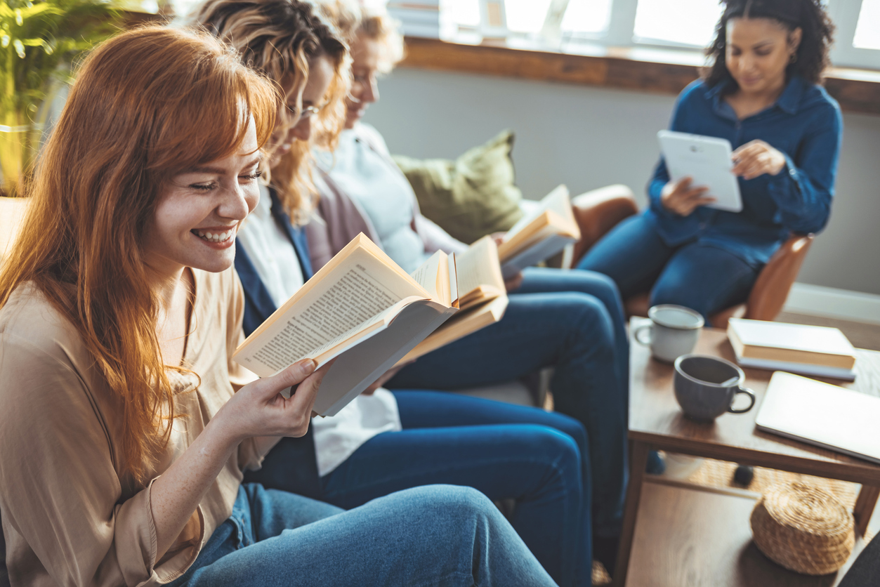 Group of women sitting together and taking part in a book club at home.