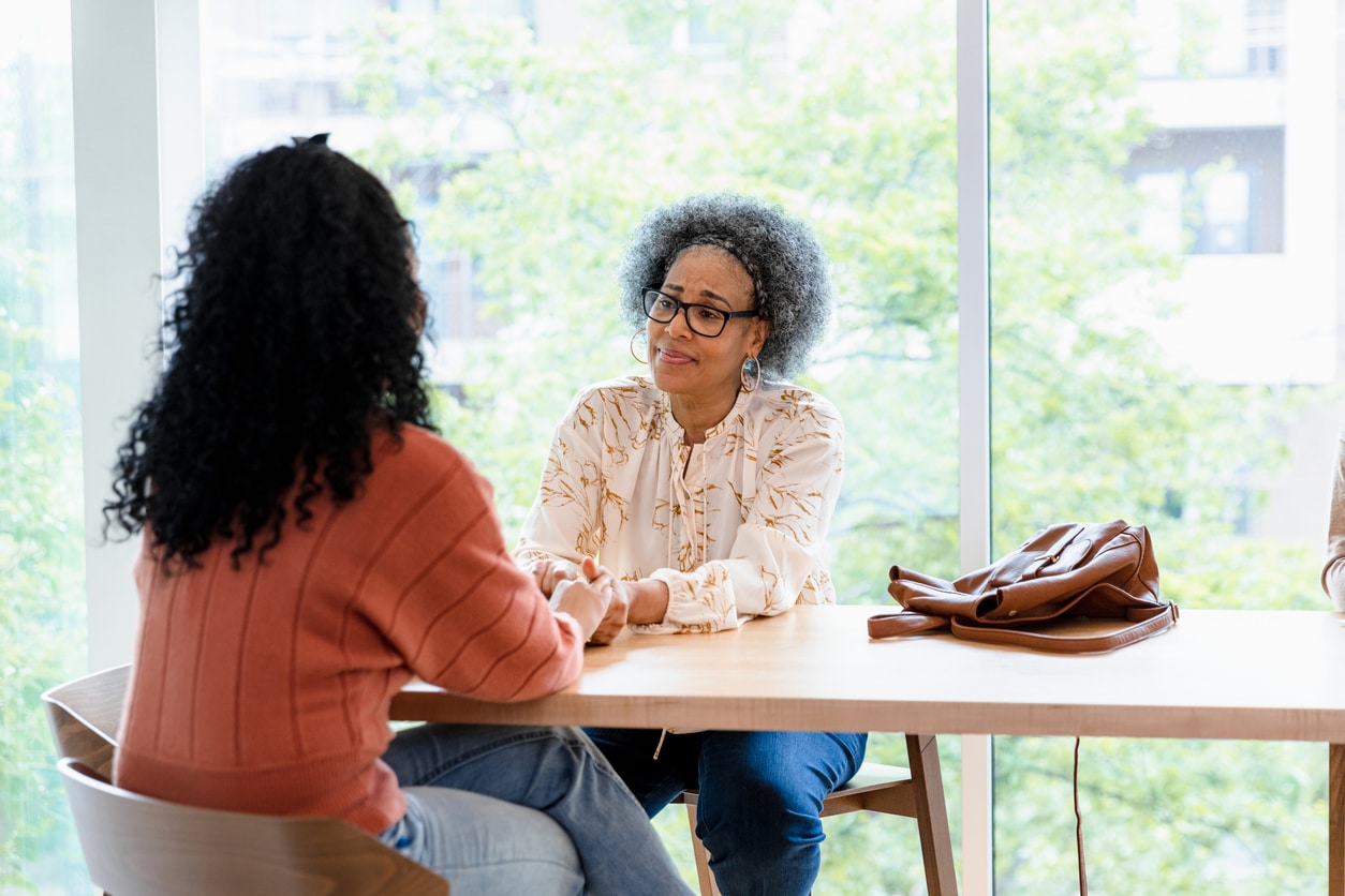 Senior manager consoles woman employee at a coffee shop.