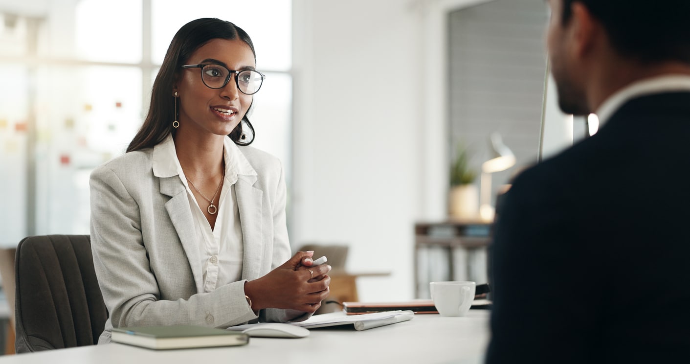 Young professional woman interviewing with an unrecognizable man in the office.