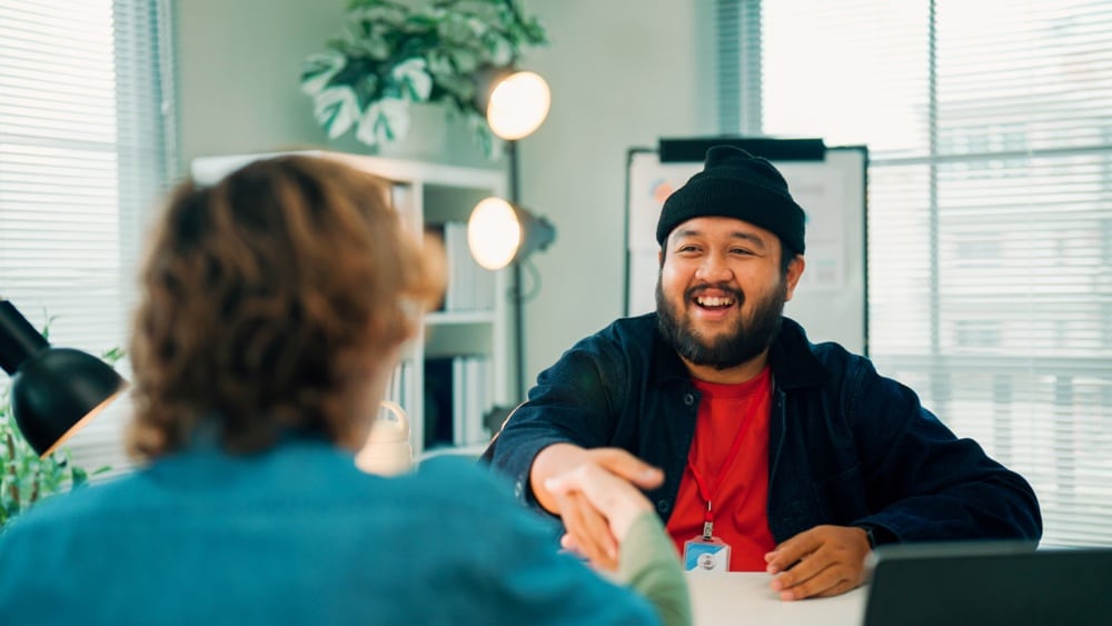 A young Asian man shaking hands with the human resource officer after he passed the interview and got an offer.