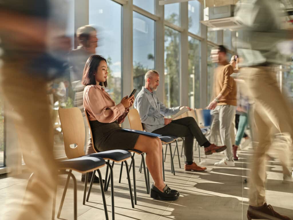 Business people waiting for job interview among their colleagues in blurred motion.